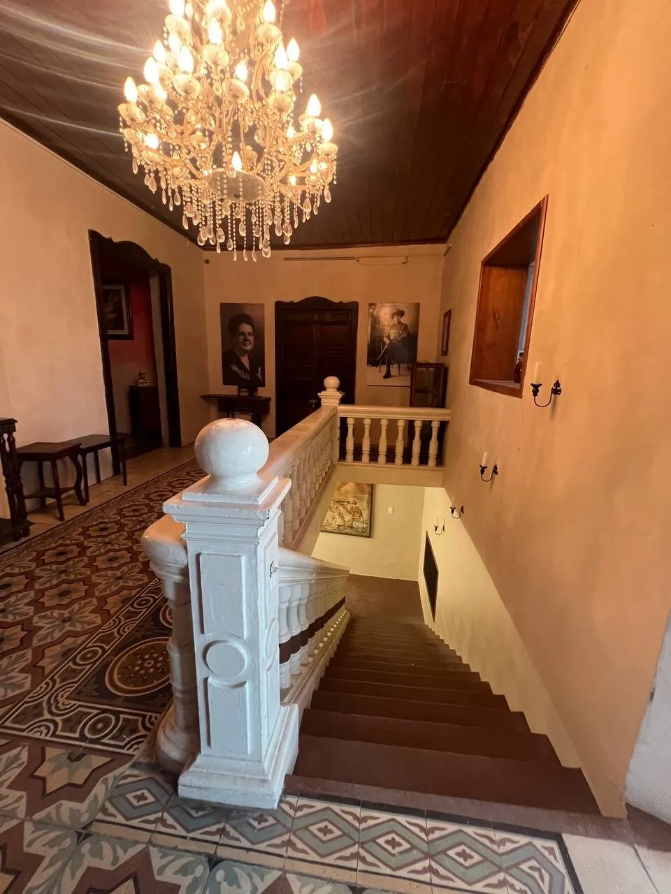 Escalera con balaustrada blanca bajo un candelabro de cristal